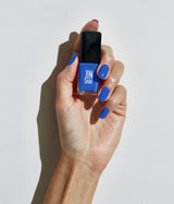 Hand with fair skin tone wearing JINsoon Cool Blue nail polish against a white background