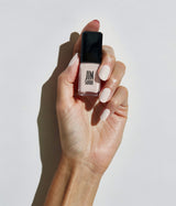 Hand with light skin tone wearing JINsoon Doux nail polish against a white background