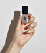 Hand with light skin tone wearing JINsoon Milieu nail polish against a white background