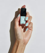 Hand with light skin tone wearing JINsoon Peace nail polish against a white background