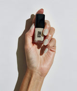 Hand with light skin tone wearing JINsoon Piedra nail polish against a white background