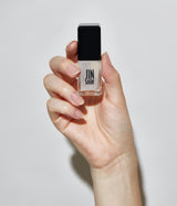 Hand with light skin tone wearing JINsoon Power Coat base coat against a white background