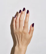 Pale hand with deep plum-purple color on the nails