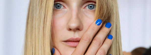 model with blonde hair and blue eyes posing with blue nails