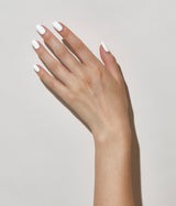 Hand with light skin tone wearing JINsoon Absolute White nail polish against a white background