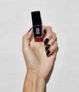 Hand with fair skin tone wearing JINsoon Absolute Black nail polish against a white background