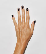 Hand with medium skin tone wearing JINsoon Absolute Black nail polish against a white background