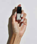Hand with light skin tone wearing JINsoon Grace nail polish against a white background