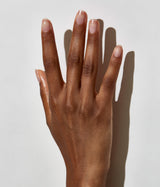 Hand with dark skin tone wearing JINsoon HyperGloss top coat against a white background