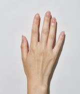 Hand with light skin tone wearing JINsoon Top Gloss top coat against a white background
