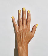 A close-up of a hand with neatly manicured yellow fingernails