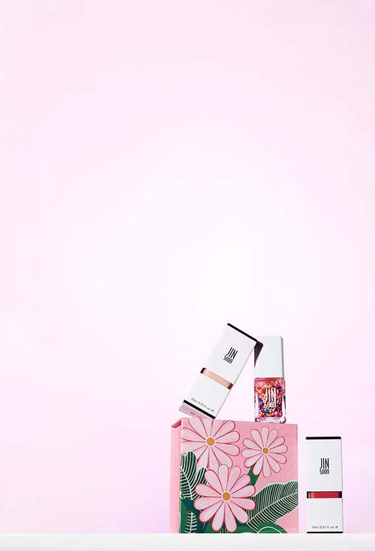 Nail polishes with a pink floral box on a light pink background